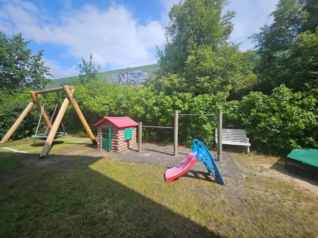 Garten des Kinderladens mit Rutsche, Schaukel, Häuschen, Bank